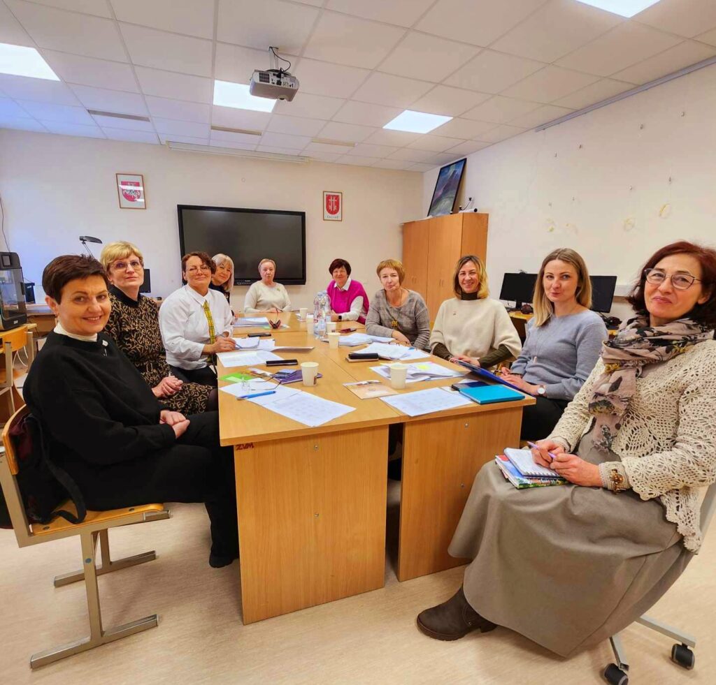 Group of professionals engaged in a meeting around a conference table, discussing projects and sharing ideas in a well-lit office environment.